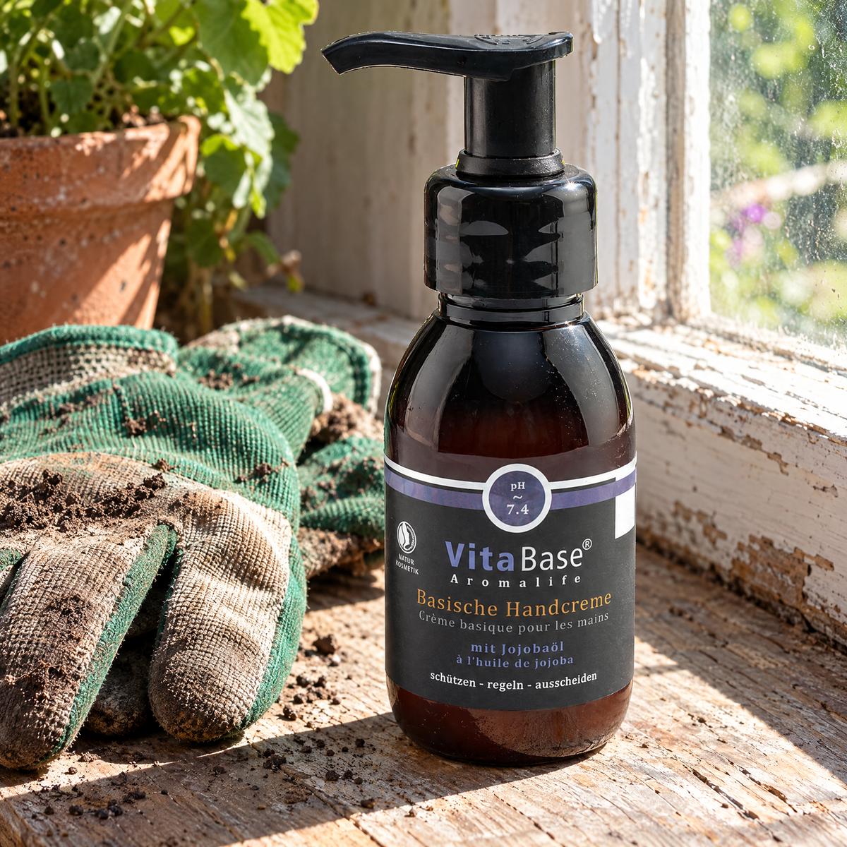 VitaBase Basische Handpflege mit Jojobaöl 100 ml – auf einer Fensterbank neben Gartenhandschuhen