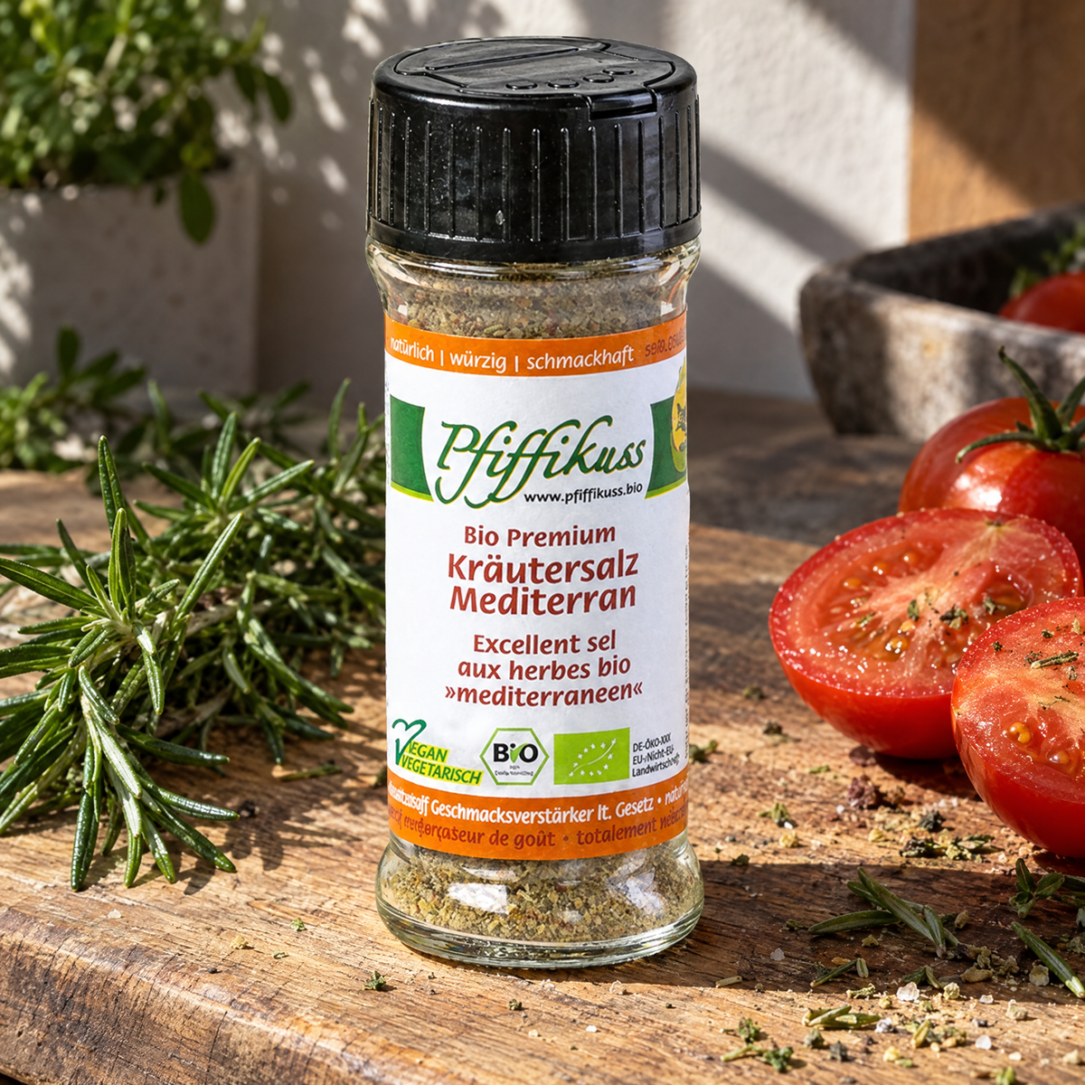 Pfiffikuss BIO Kräutersalz mediterran 75 g – auf einem Holzbrett neben Rosmarin und Tomaten