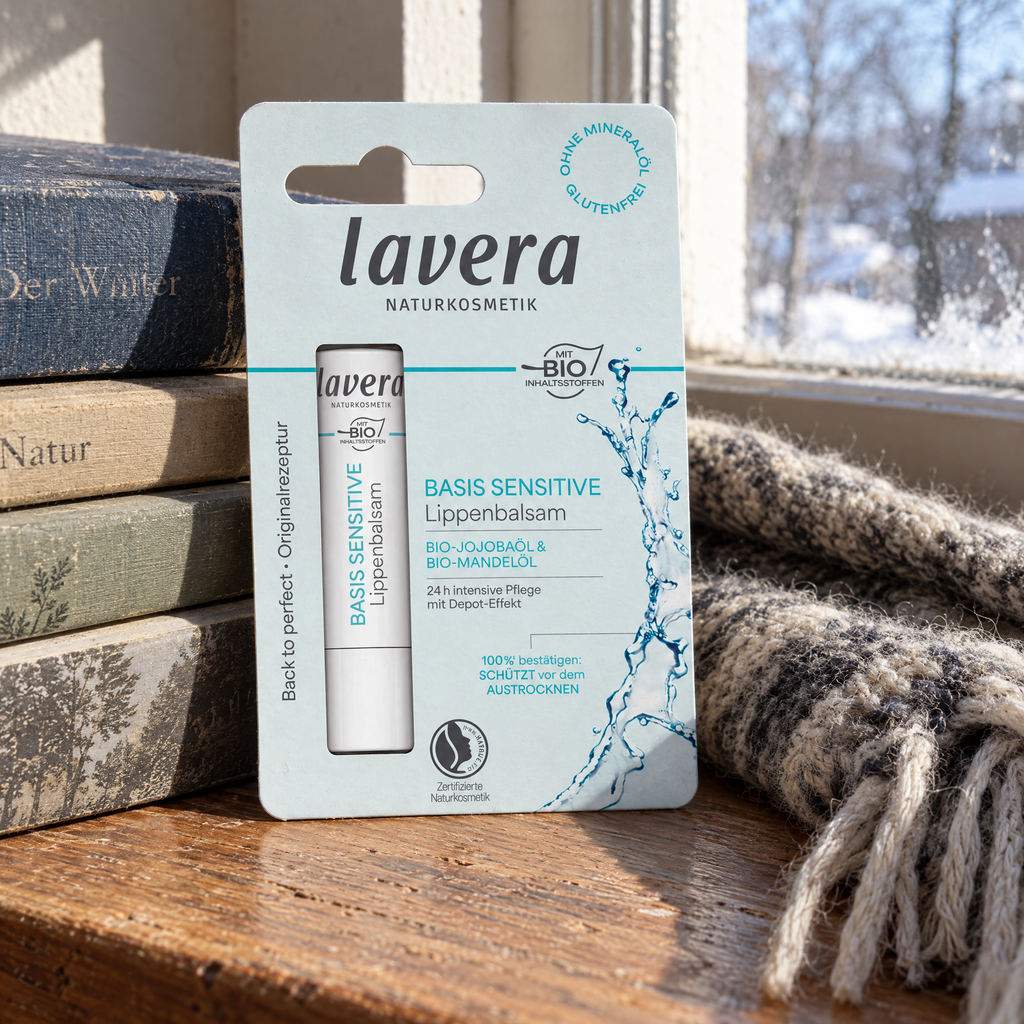 Lavera Basis Sensitiv Lippenbalsam 4,5 g – auf einer Fensterbank neben Büchern und Wollschal