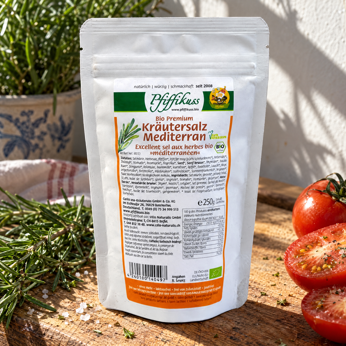 Pfiffikuss BIO Kräutersalz mediterran 250 g – auf einem Holzbrett neben Rosmarin und Tomaten