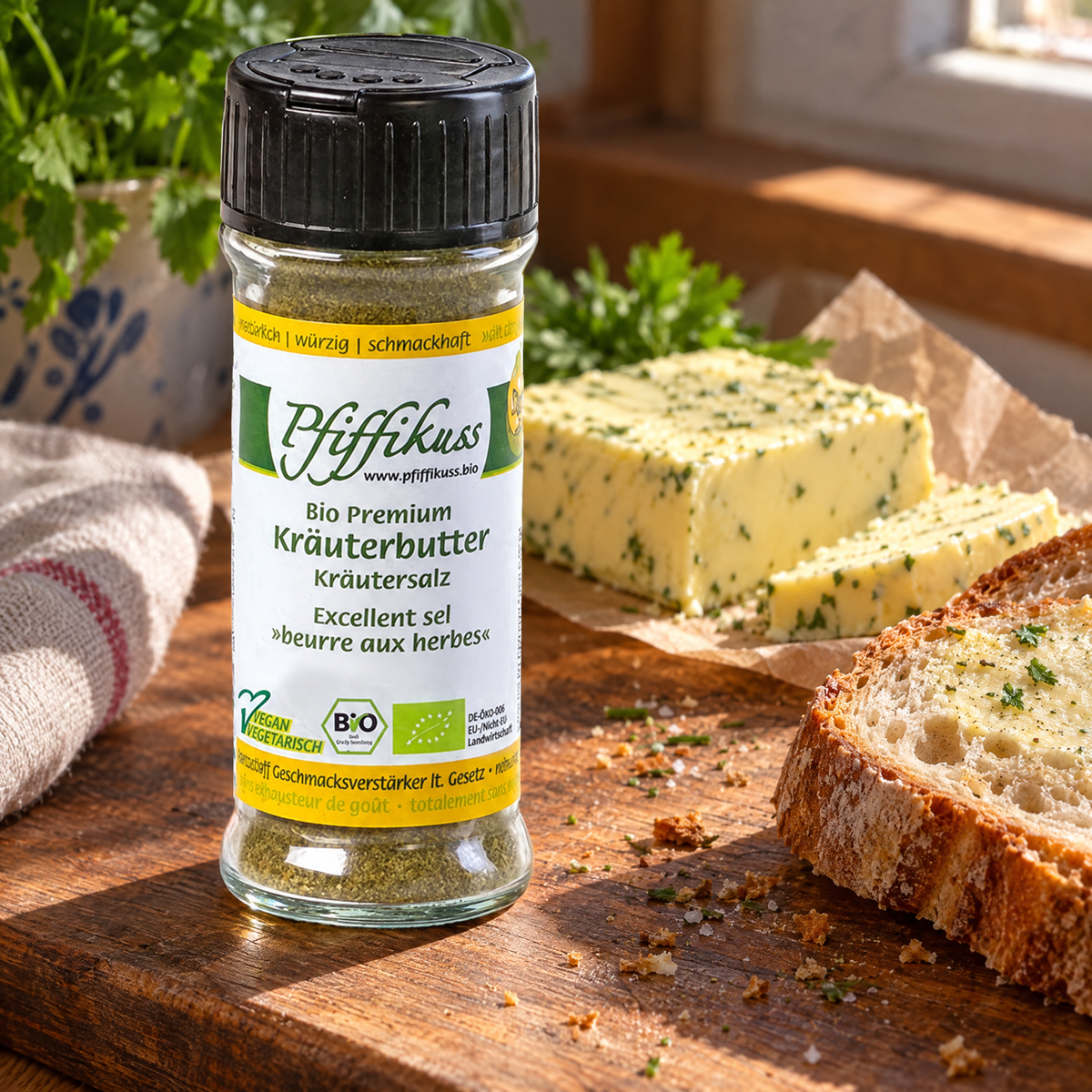 Pfiffikuss BIO Kräuterbutter-Gewürzsalz 70 g – auf einem Holzbrett neben Butter und Brotscheiben