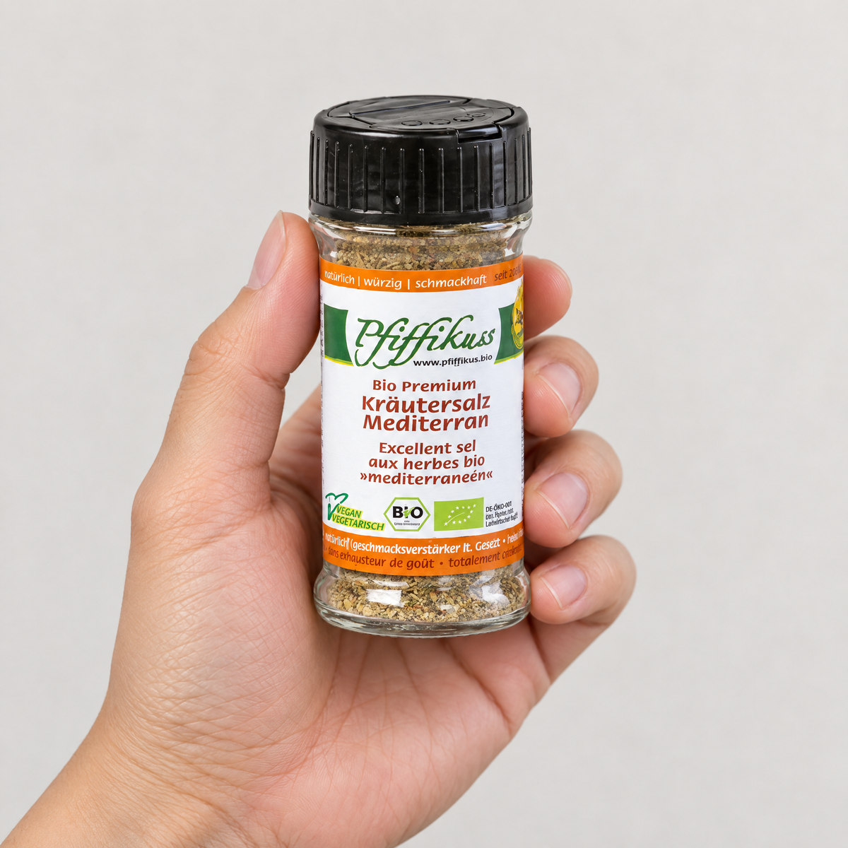 Pfiffikuss BIO Kräutersalz mediterran Streuglas 75 g in einer Hand – Grössenvergleich